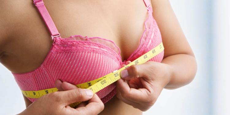 Mature woman holding a tape measure over her bra Stock Photo