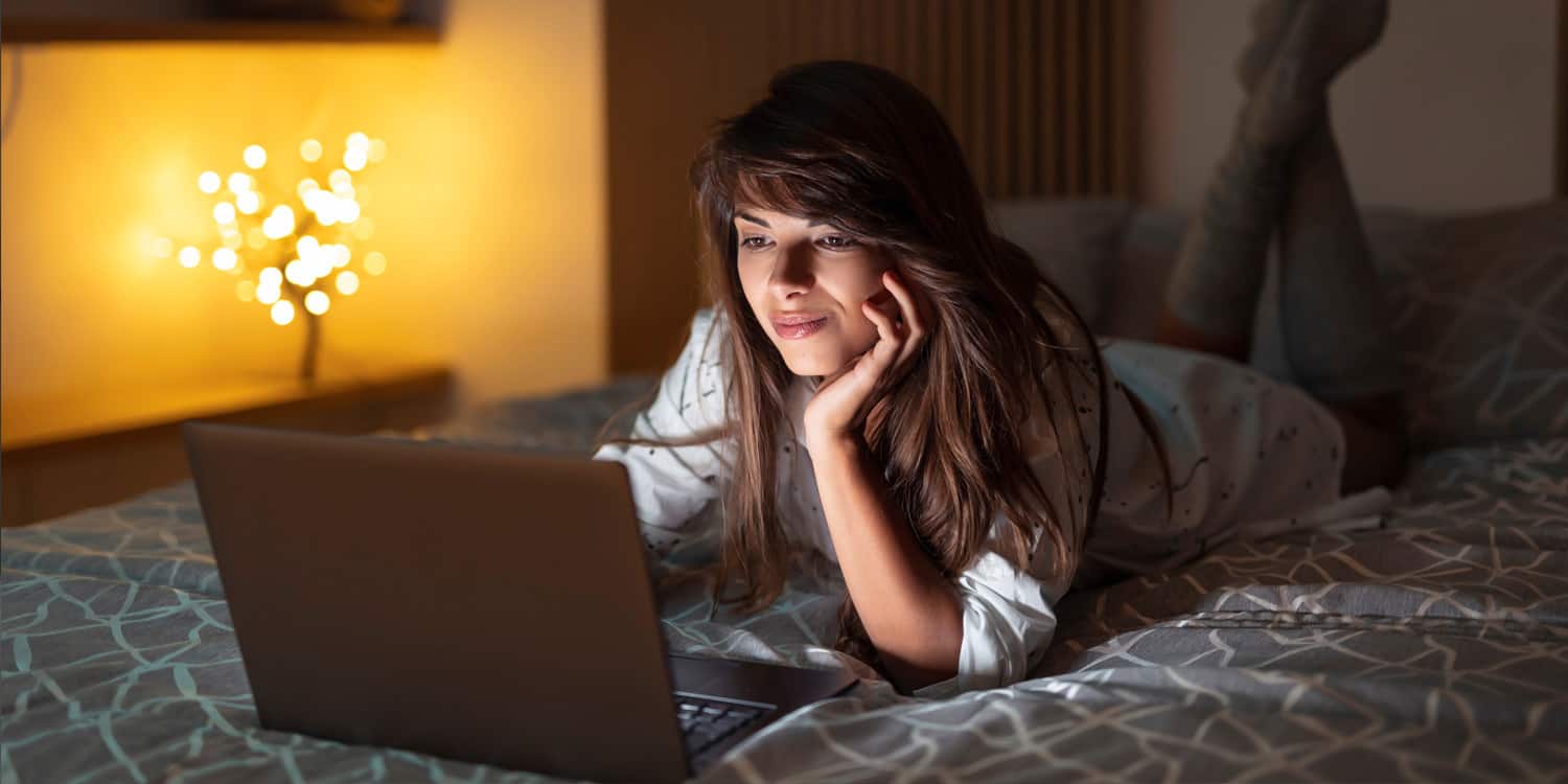 woman watching vide on laptop computer in bed at night